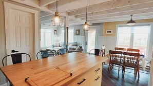 Een keuken met een houten keukeneiland, hanglampen en een eethoek met houten stoelen en een tafel.