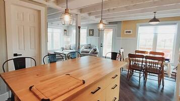 A kitchen with a wooden island, pendant lights, and a dining area with wooden chairs and a table.