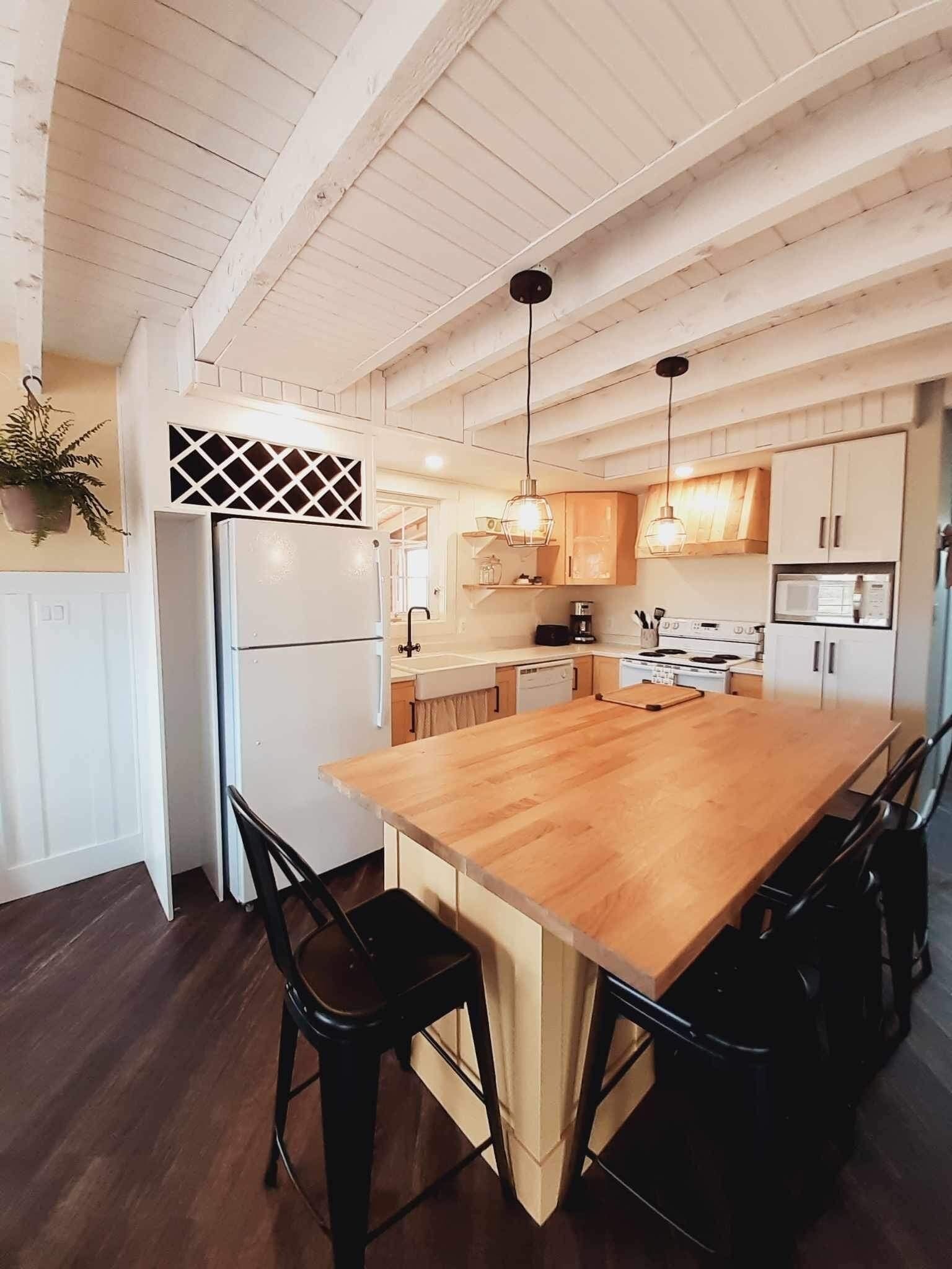 A kitchen with a wooden island, white cabinets, and a hanging light fixture.