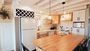 Een keuken met een houten kookeiland, witte kastjes en een hanglamp.