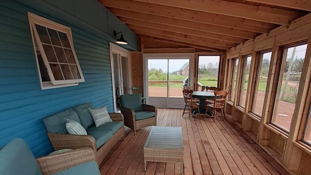 Een overdekt terras met rieten meubels, een tafel en stoelen.