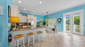 A kitchen with white cabinets, a bar area with stools, a fire extinguisher, and a clock on the wall.