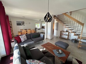 Uma sala de estar moderna com sofá, mesa de centro e escada.