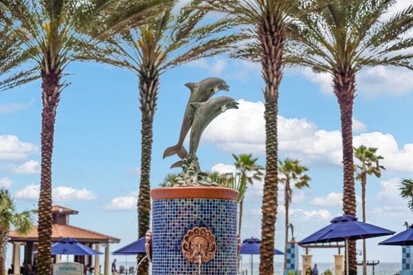 A decorative fountain with dolphins, surrounded by palm trees and umbrellas. - Shores of Panama studio - Gulf views (Panama City Beach)