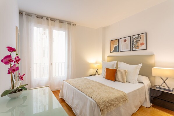 A hotel room with a bed, bedside tables, a desk, and a potted orchid. - Cozy 2BR Apartment Steps from Plaza Mayor (Madrid)