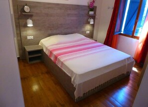 Cozy bedroom with a single bed, wall-mounted lights, and a shelf for personal items.