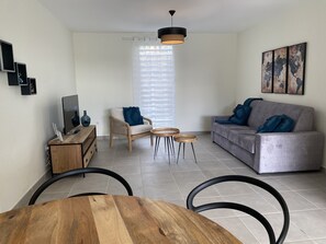Un salon moderne avec un canapé gris, une table basse en bois et un téléviseur posé sur un meuble en bois.
