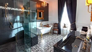 A luxurious bathroom with a freestanding bathtub, a glass-enclosed shower, and a marble sink.