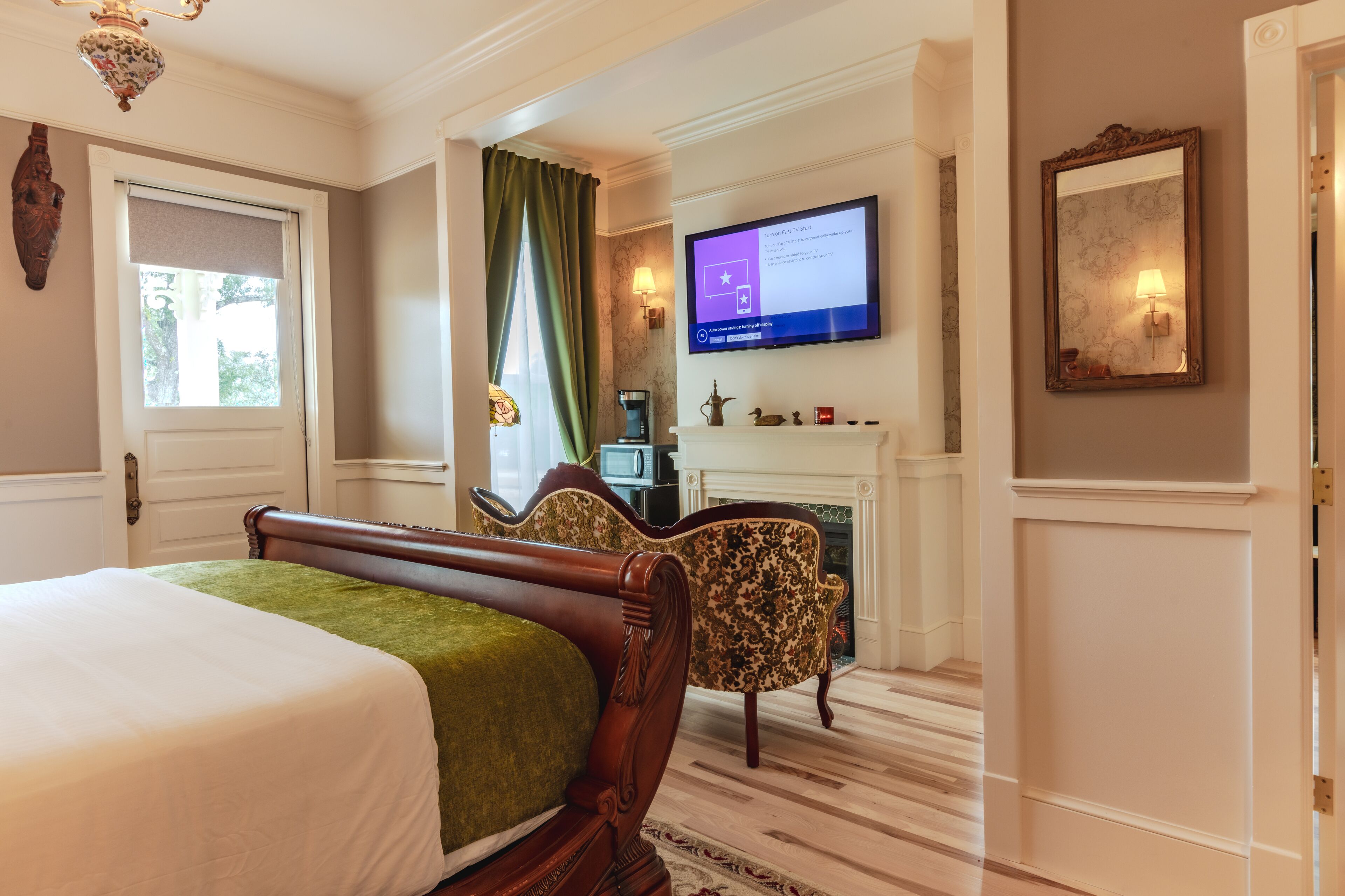 Une chambre d’hôtel avec un grand lit, un téléviseur fixé au mur, une cheminée et un miroir.