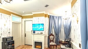A living room with a fireplace, a television, a coffee maker, and a dining area.