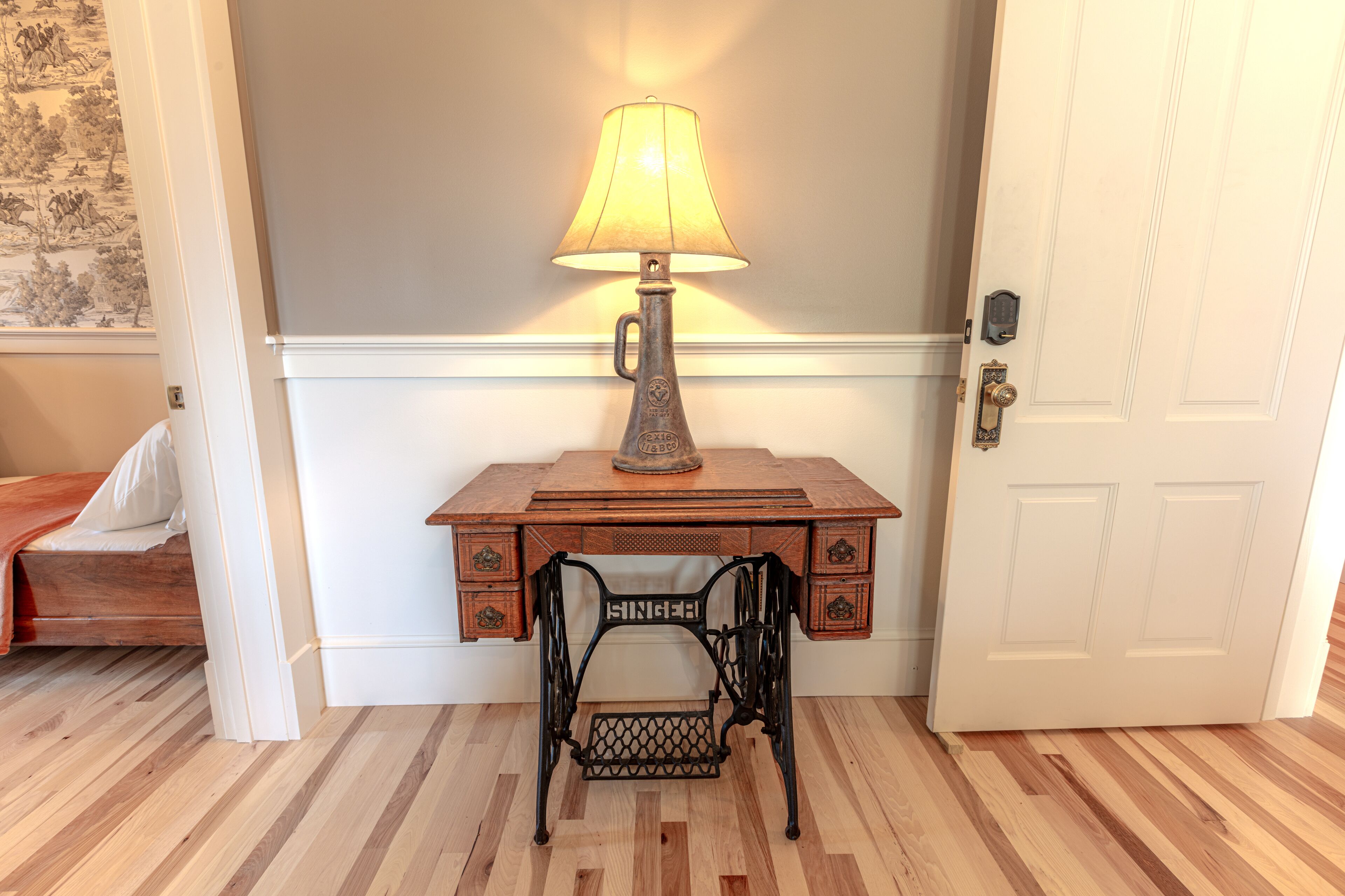 A wooden desk with a lamp, a chair, and a door.