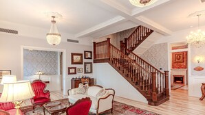 A spacious living room with a grand staircase, elegant furniture, and a fireplace.