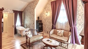 A room with a clawfoot bathtub, a vintage sofa, a marble coffee table, and a chandelier.