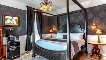 A four-poster bed with a dark headboard, a chandelier, and two bedside tables with lamps.