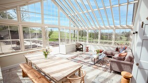A conservatory with a table, chairs, a sofa, and a view of the outdoors. - 4 bedroom accommodation in Broughton, near Skipton (Broughton, near Skipton)