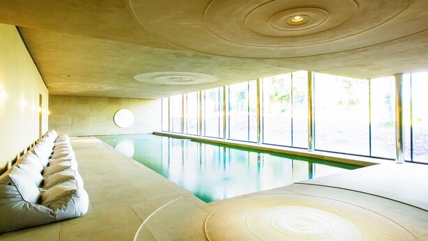 A modern indoor swimming pool with a sunlit room featuring a long bench and a circular design on the ceiling. - 4 bedroom accommodation in Broughton, near Skipton (Broughton, near Skipton)