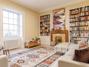 A living room with a fireplace, bookshelves, a patterned rug, and a sofa.