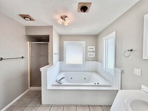 Une salle de bain avec une grande baignoire, une douche, des toilettes et un lavabo.