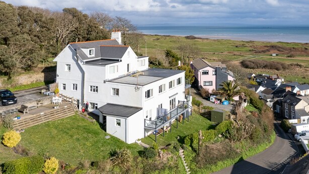 A large white house with a flat roof, a balcony, and a view of the sea. - The Cwtch Apartment - Sea Views, Walk to Beach (Penally)