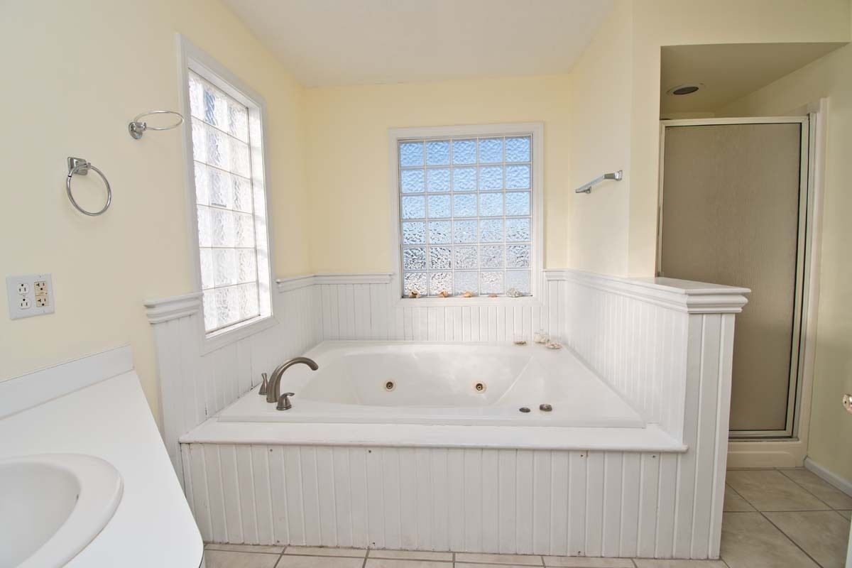 Une salle de bain avec une grande baignoire, une fenêtre à verre dépoli et un espace douche.