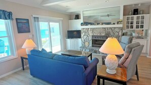 Ein Wohnzimmer mit einem blauen Sofa, einem grauen Sessel, einem Couchtisch und einem Kamin.