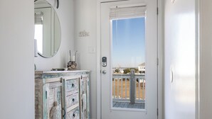 Puerta blanca con vistas a una terraza de madera y un edificio al otro lado del agua.