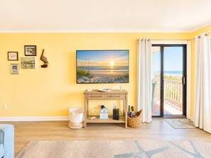 Quarto com uma grande janela, televisão de tela plana, mesa de console de madeira e vista para a praia.