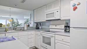 Une cuisine moderne avec des meubles blancs, un four à micro-ondes, une cuisinière et un réfrigérateur.
