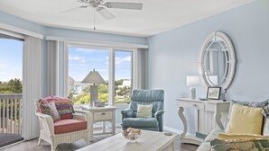 Un salon spacieux avec une table basse blanche, des fauteuils en osier et un fauteuil bleu.