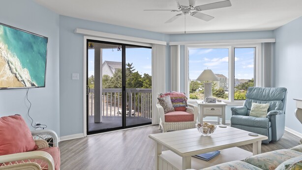 Un salon spacieux avec un balcon, des meubles en osier et une vue sur l’extérieur.
