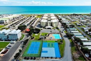 An aerial view of a resort with multiple buildings, a swimming pool, and a tennis court.