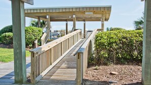 A wooden boardwalk leading to a covered area with a 'NO SKATEBOARDS' sign. - Queens Court 1204, Oceanfront Condo in Emerald Isle, NC! (Emerald Isle)
