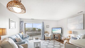 Ein modernes Wohnzimmer mit einer Couch, Sesseln, einem Couchtisch und einem Fernseher.