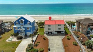 A beachfront property with a blue house, a red-roofed building, and a view of the ocean. - Red Roof Cottage East, Oceanfront Duplex in Emerald Isle, NC! (Emerald Isle)