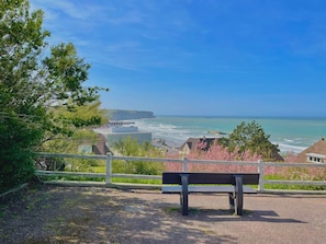 A bench overlooking a coastal view with buildings and cliffs.