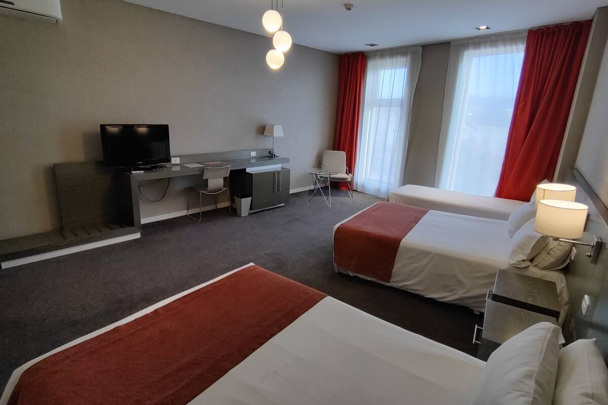 Habitació d'hotel amb dos llits, una taula de treball amb televisió, una cadira i una làmpada.