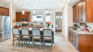 Una cocina moderna con gabinetes de madera, electrodomésticos de acero inoxidable y una isla central con sillas.