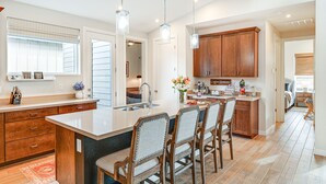 Una cocina moderna con una isla grande, armarios de madera e iluminación colgante.