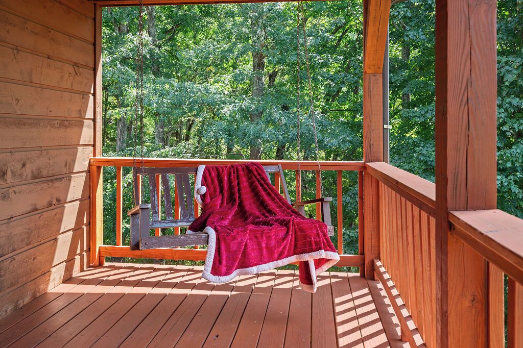 A wooden deck with a bench and a red blanket.