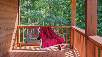 A wooden deck with a bench and a red blanket.