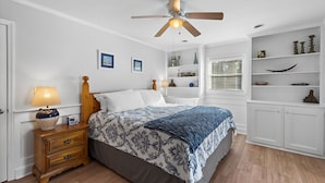 Un dormitorio con cama, mesita de noche y estanterías empotradas.