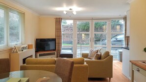 A modern living room with a sofa, a TV, and a dining table. - Leven Lodge 2 - UK46044 (Loch Lomond)