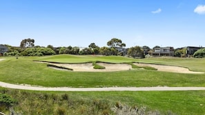 A golf course with bunkers and a clear sky.