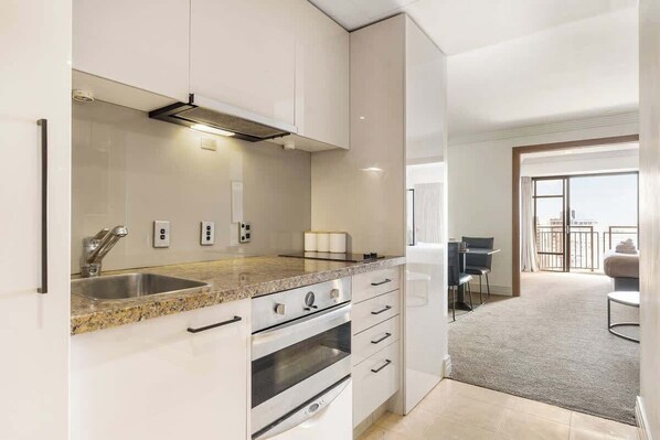 A modern kitchen with a granite countertop, stainless steel appliances, and a view to a balcony. - Stunning City Views - w Pool&Gym (Auckland)