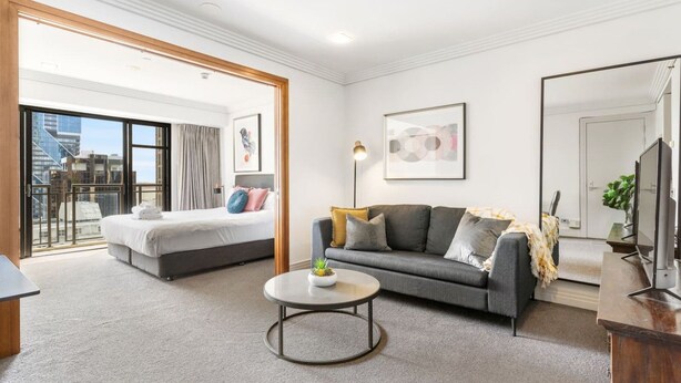 A modern hotel room with a bed, sofa, and a small coffee table. - Stunning City Views - w Pool&Gym (Auckland)