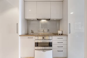 A compact kitchen with white cabinets, a stainless steel oven, and a granite countertop.