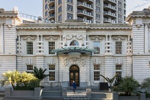 A large, historic building with a grand entrance, multiple windows, and a central clock.