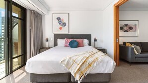 A modern hotel room with a large bed, two bedside tables, a sofa, and artwork on the walls. - Stunning City Views - w Pool&Gym (Auckland)