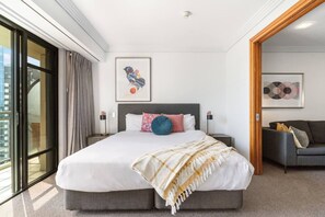 A modern hotel room with a large bed, two bedside tables, a sofa, and artwork on the walls.