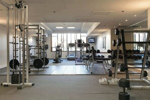 A gym with weightlifting equipment, treadmills, and a television screen. - Stunning City Views - w Pool&Gym (Auckland)